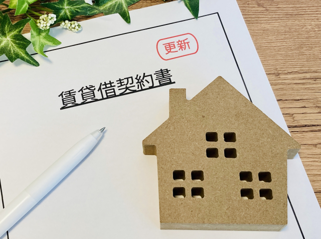 賃貸借契約書の上にペンと家の模型を置いている写真