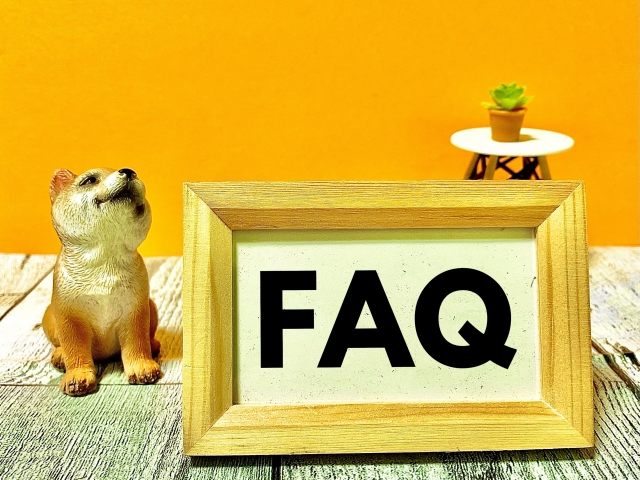 「FAQ」と書かれ額縁の隣に、置物の犬が座っている